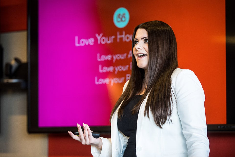 ASU alumna Demi George speaks in front of a projector screen 