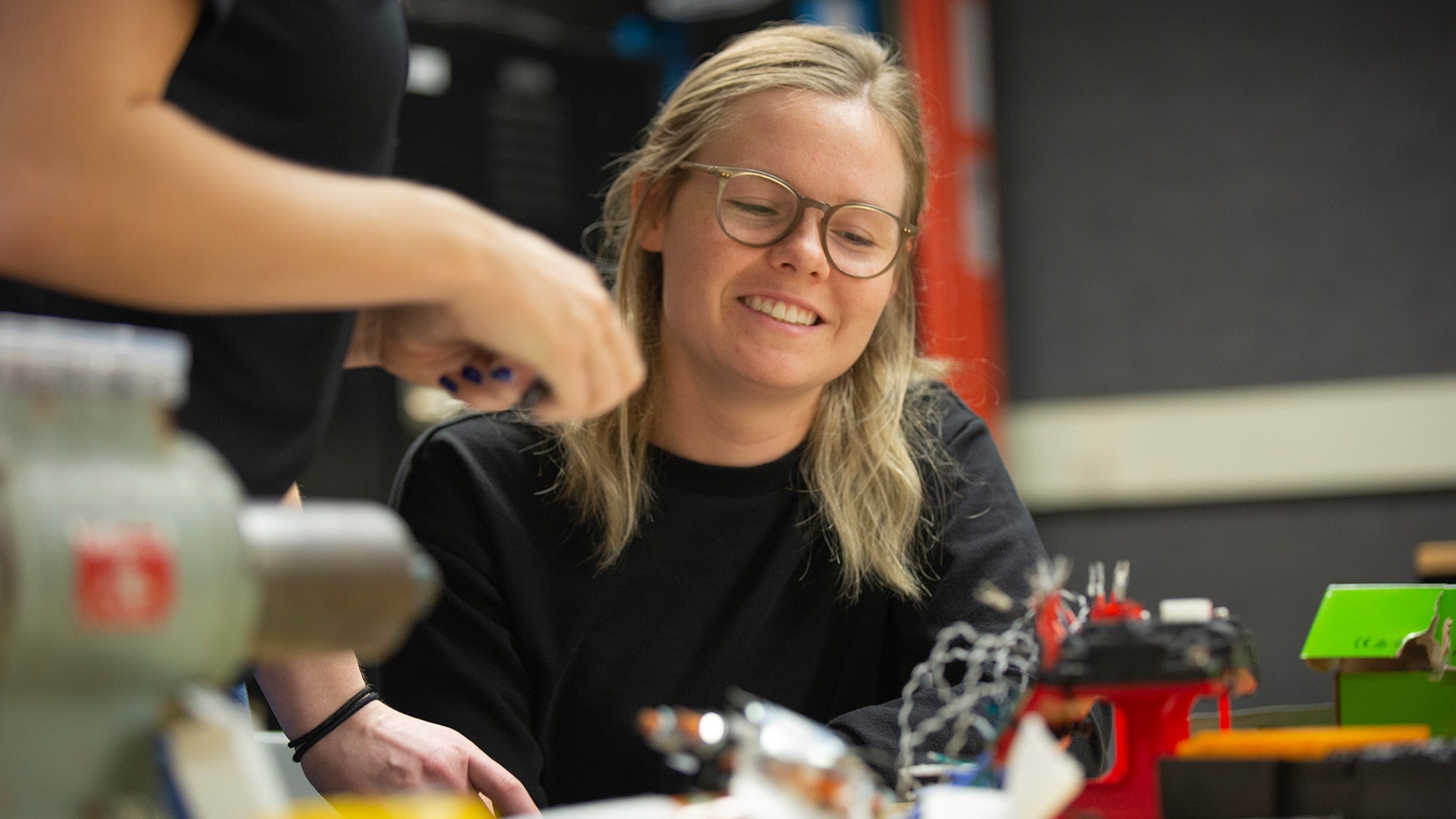 ASU student Andrea Schoonover smiling while working with teammates at a robotics competition.