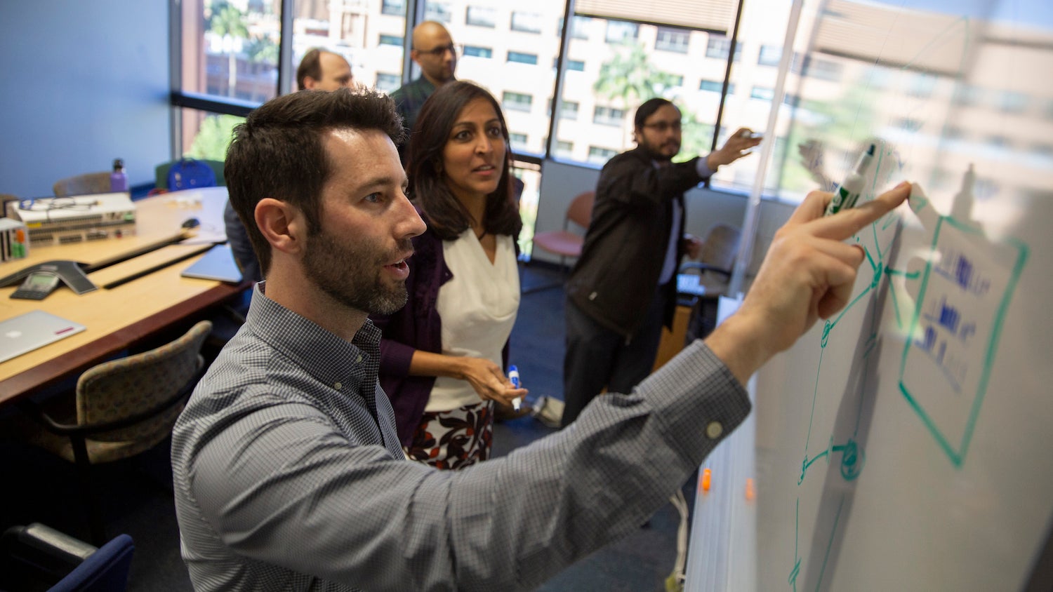 group of people interacting with a white board