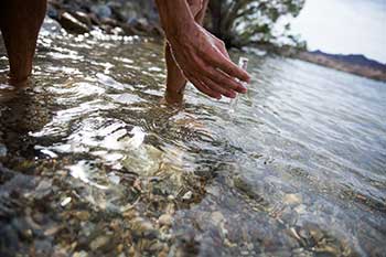 A researcher gathers a vial of water from a river