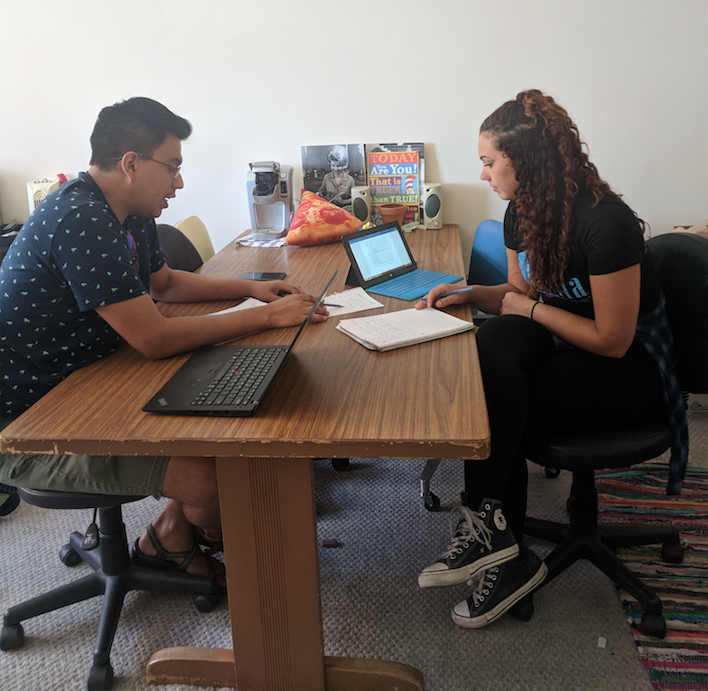 Edwin Vazquez sitting with student at small table reviewing notes.