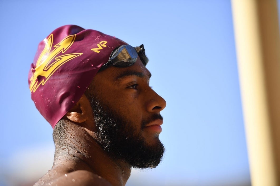 Close-up of ASU student Elijah Warren wearing goggles and a maroon swim cap with a gold trident.