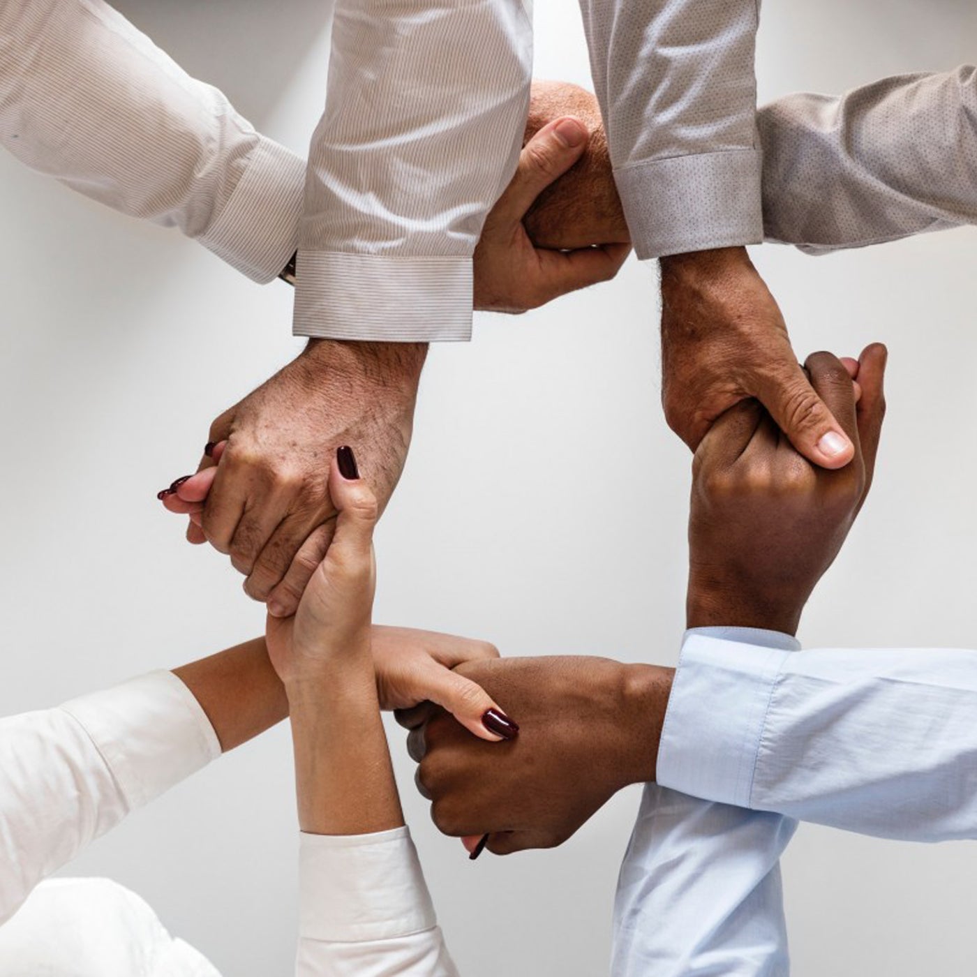 overview of four people holding hands, with the hands and arms making a square shape