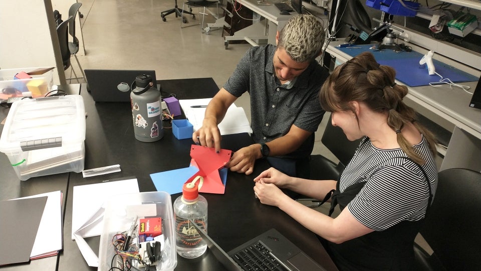 Students working on an origami device at an engineering camp.