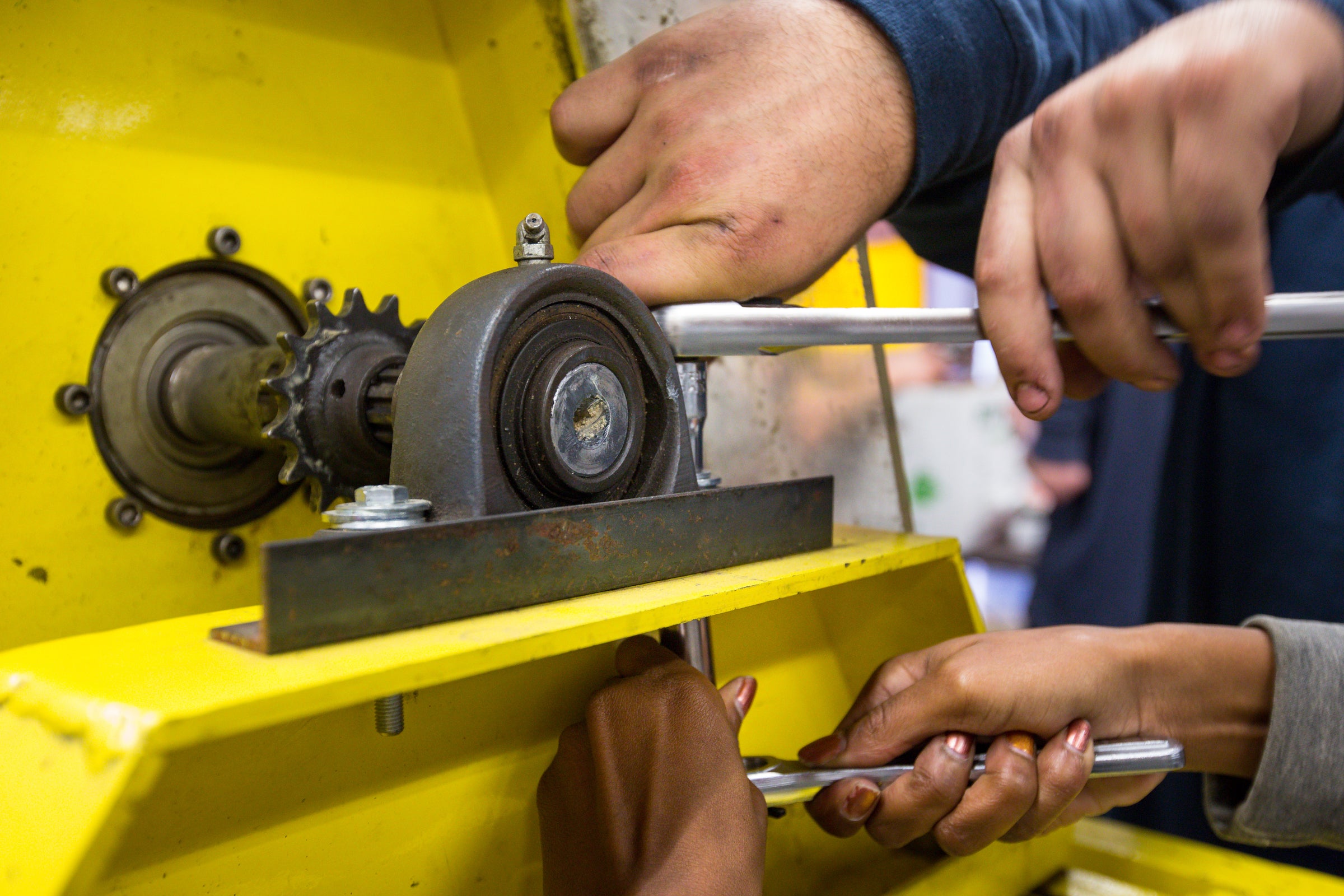 Hands of students shown in a closeup working on an engine.