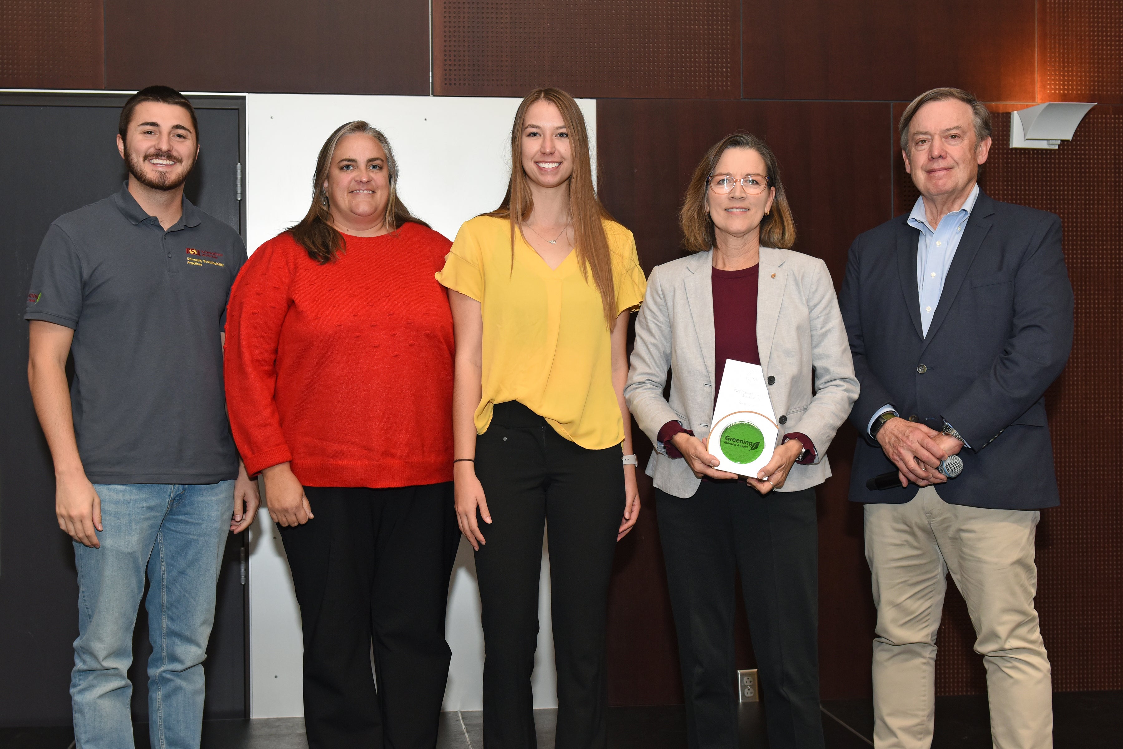 Group of people on stage posing with award