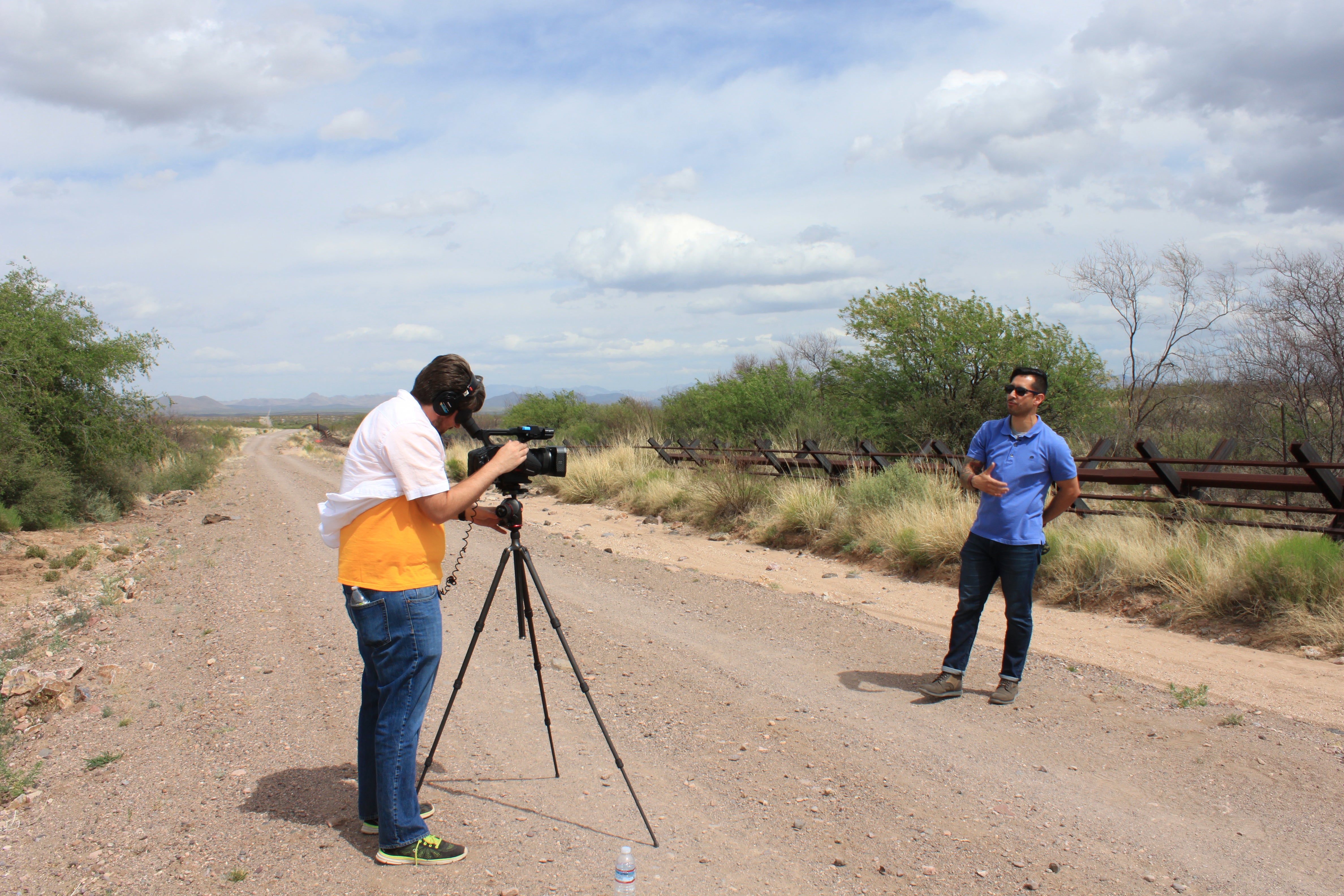 man with camera filming man speaking