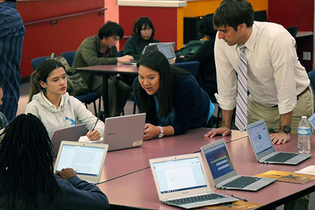 Hamilton Education Program teachers work with students around a table