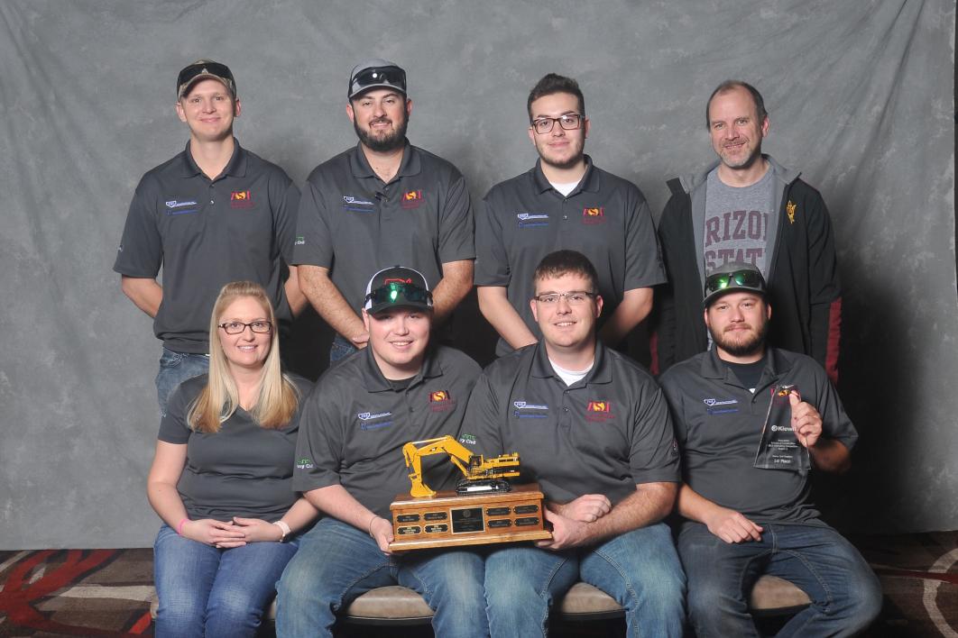 Photo of eight people posed holding a trophy.