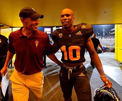 ASU football Coach Herm Edwards and a player walk through the Tillman Tunnel