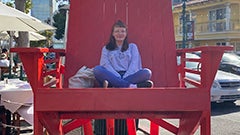 Young woman sitting in an oversized red wooden chair