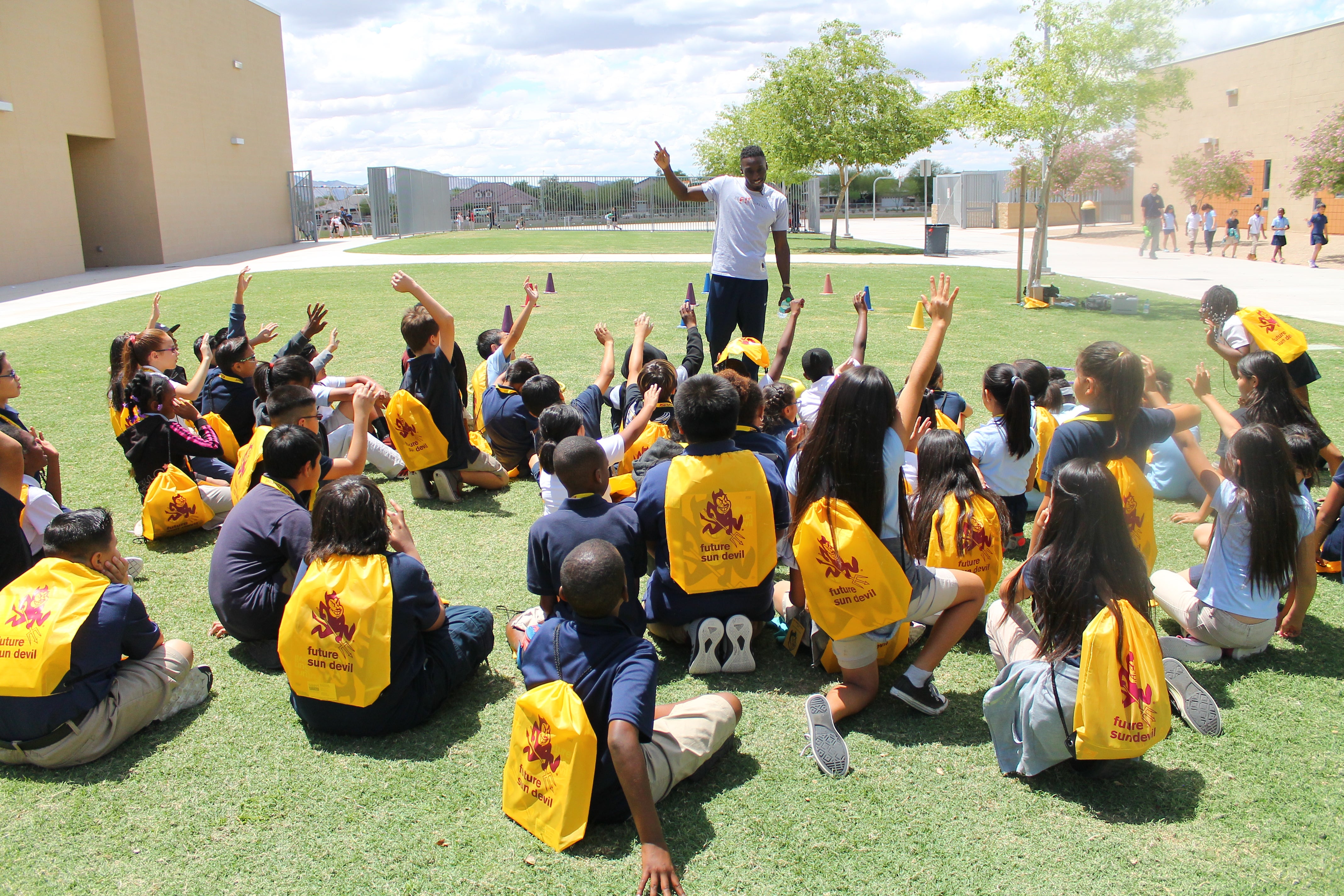 kids sitting on lawn raising hands