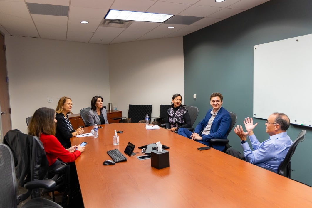 People seated at a table in a conference room talking.