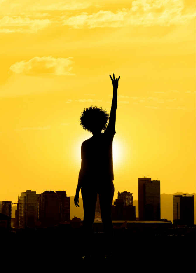 A woman raising her arm doing the pitchfork hand gesture.