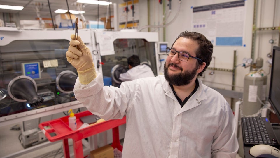 Man in lab holding up a tool.