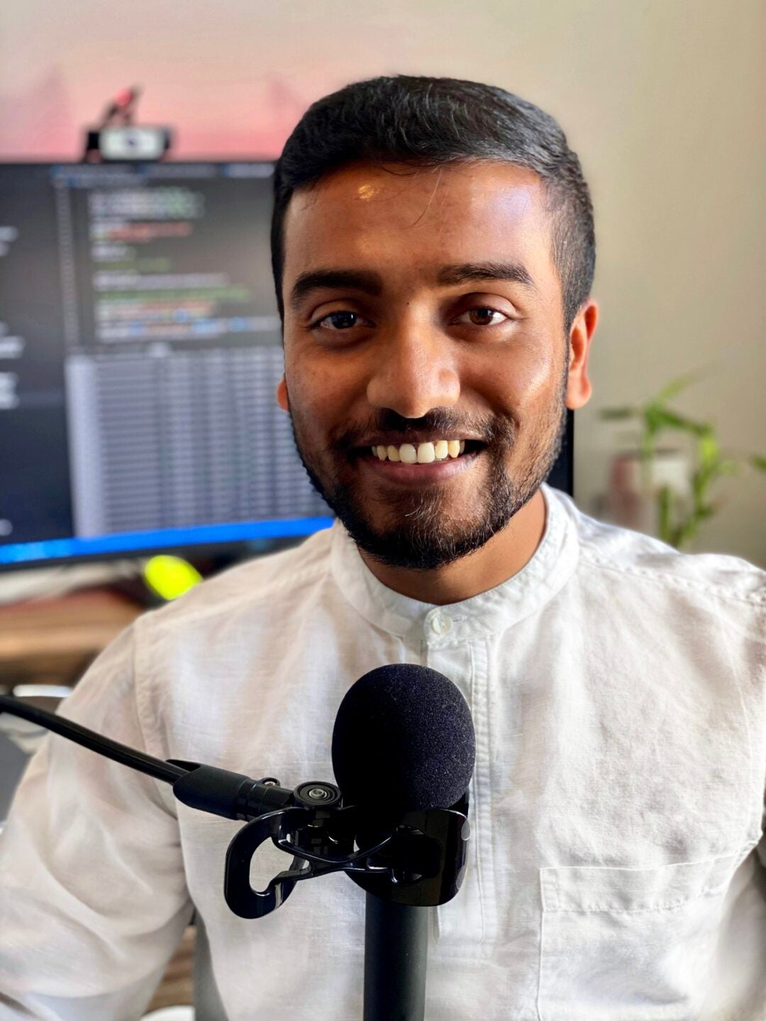 Portrait of ASU computer science doctoral student and researcher Jay Shah with a microphone.