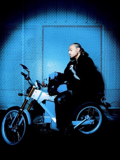 Jean Dawson sitting on a motorcycle under blue light