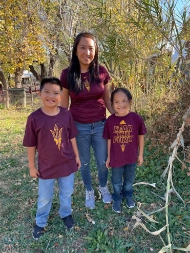 Native American woman and her two sons smiling in a wooded setting.