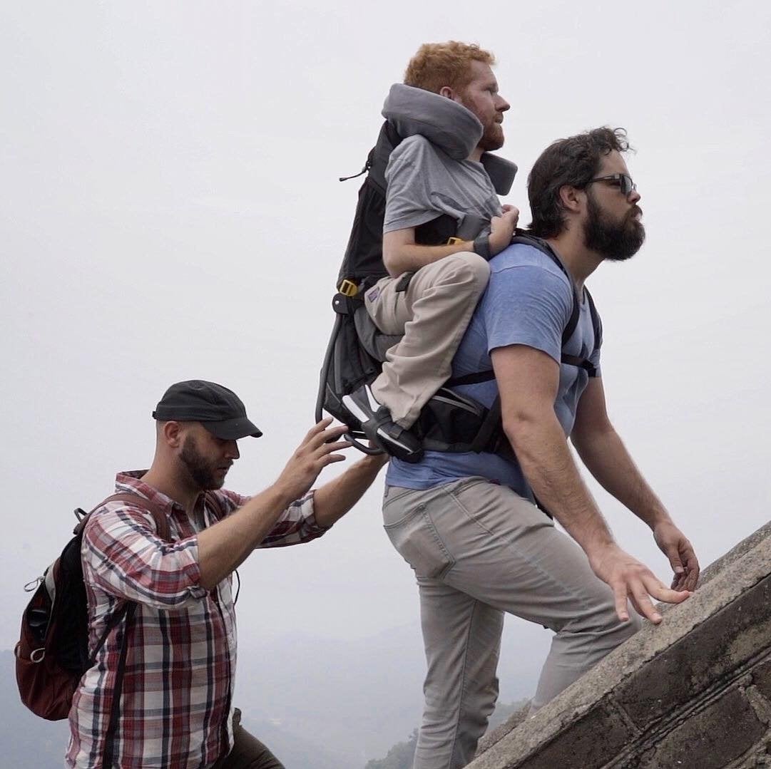 Man carrying his friend on his back as they travel along the Great Wall of China.