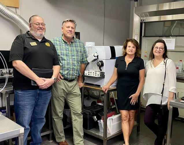 People standing in a lab around equipment, smiling.