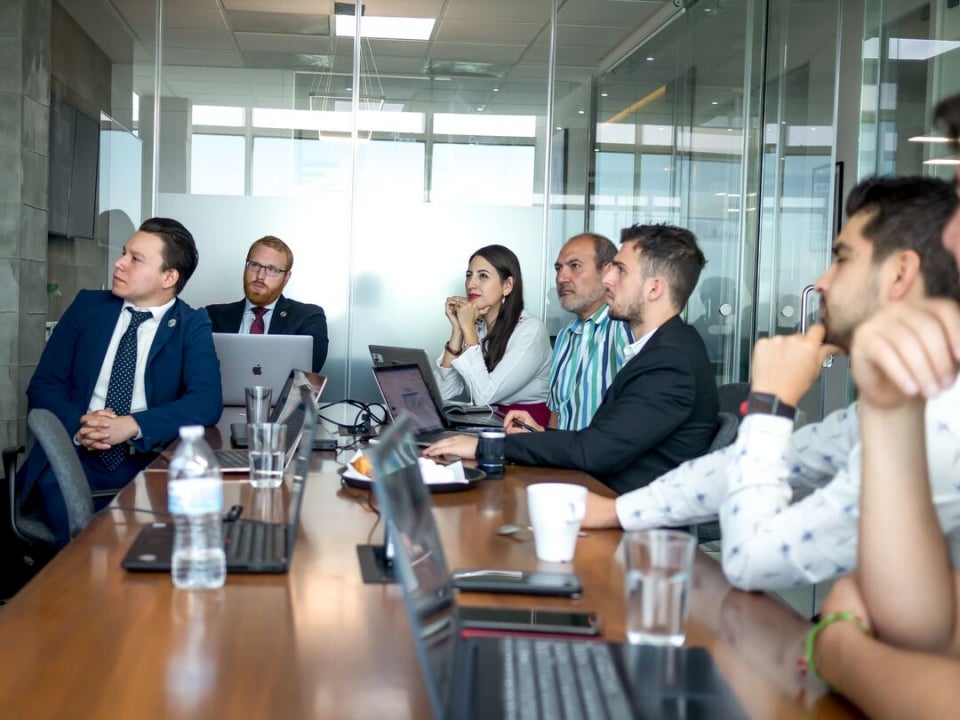 People seated at a conference table in a meeting.