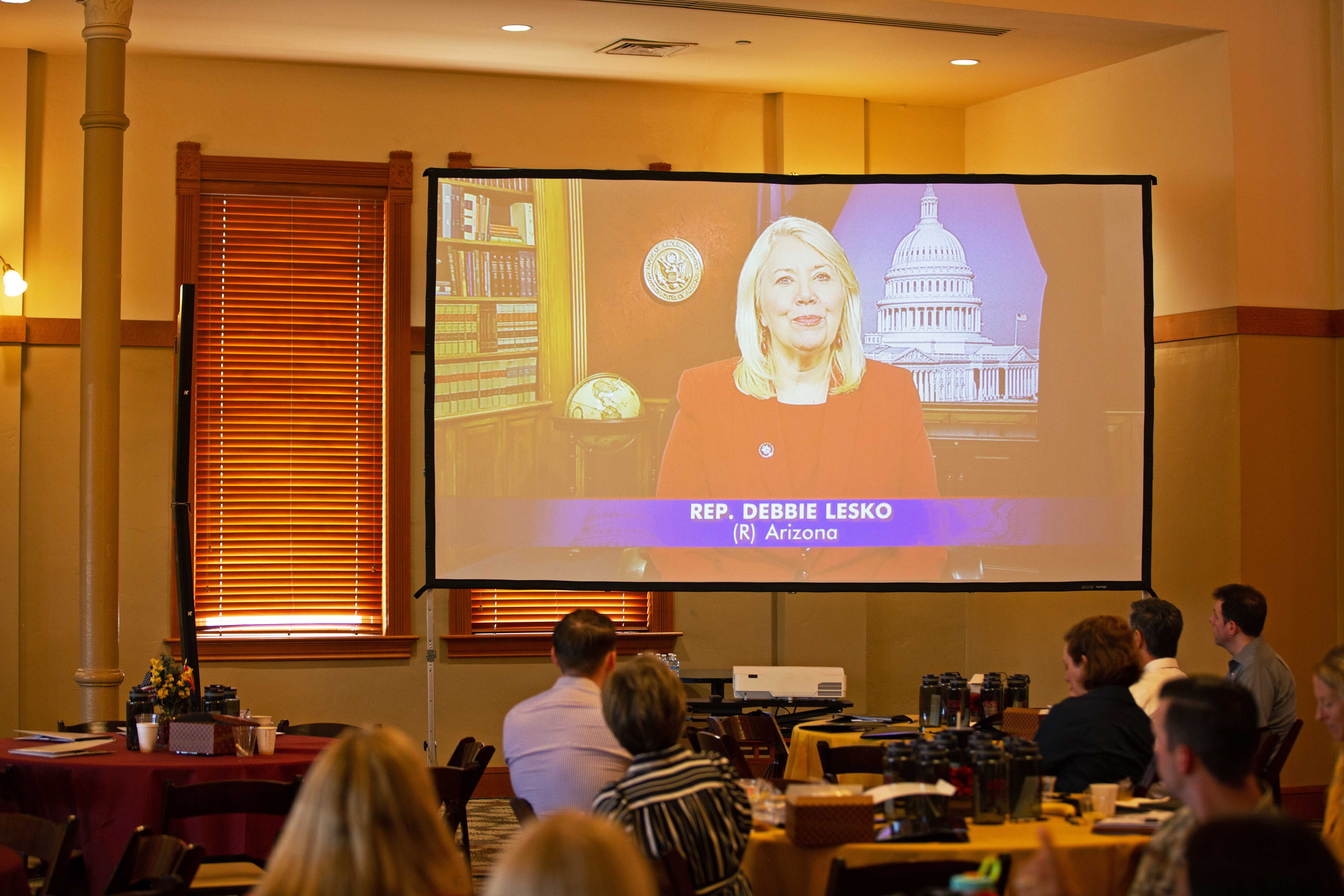 Woman speaking on screen during event