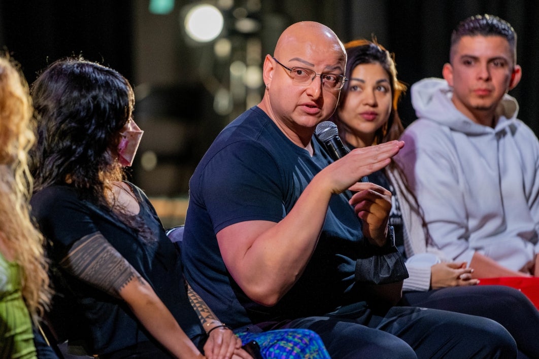 man sitting, speaking into microphone at event