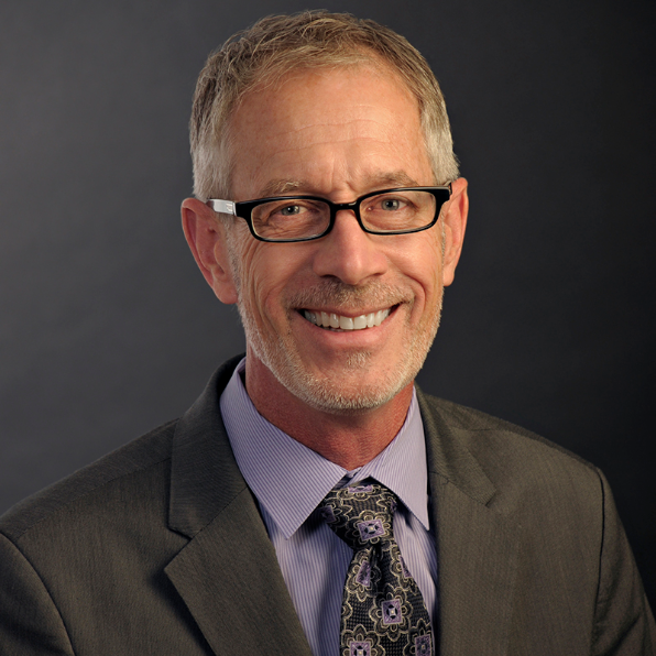 Man in purple shirt and tie smiling