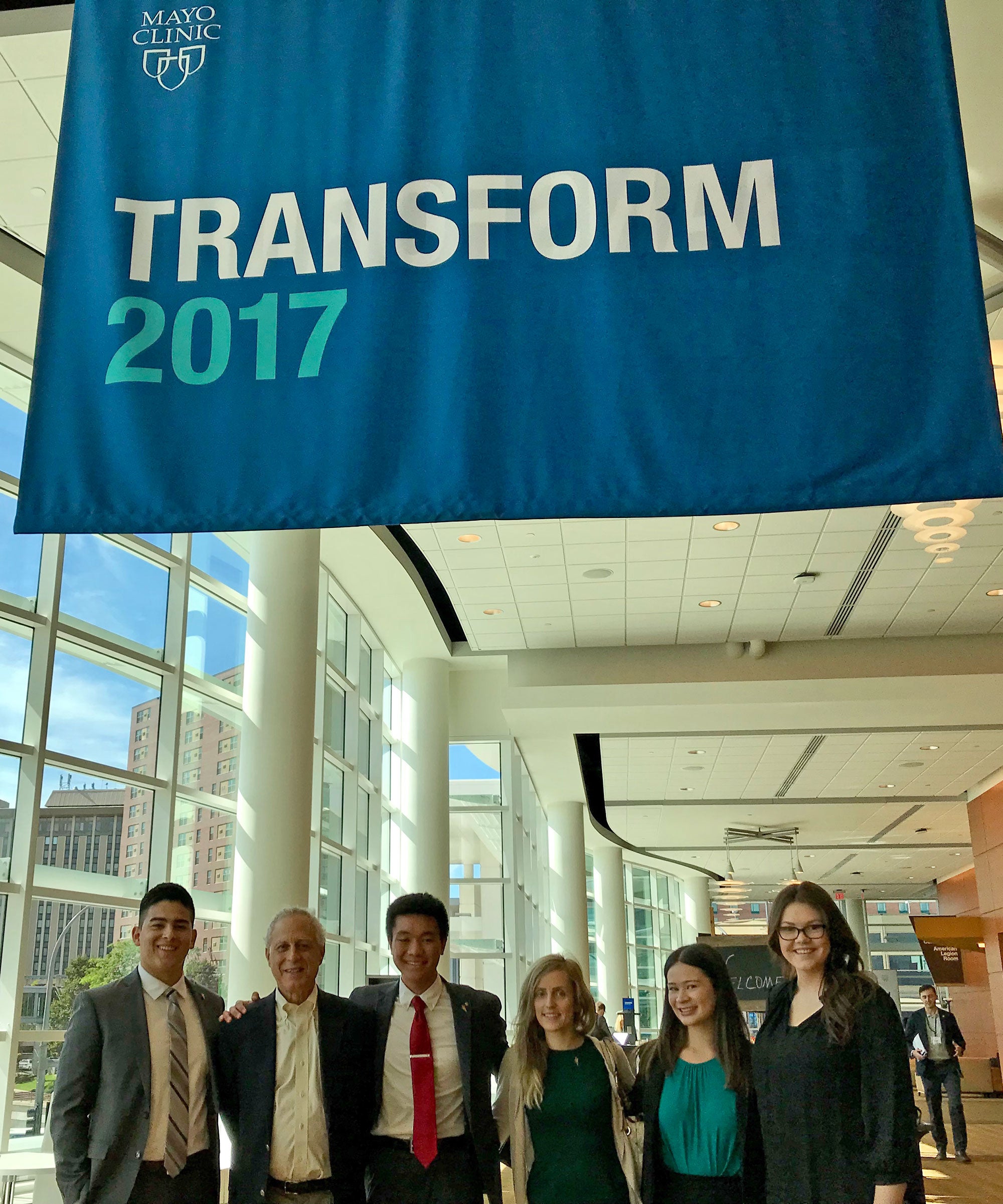 ASU students and faculty pose for a photo under a health conference banner