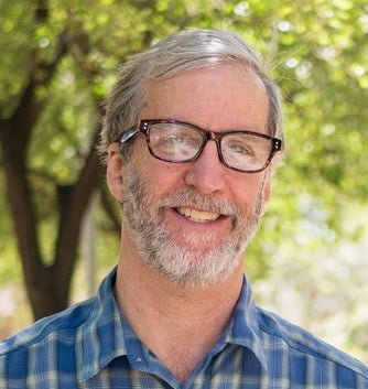 close-up of a smiling man with gray hair and glasses