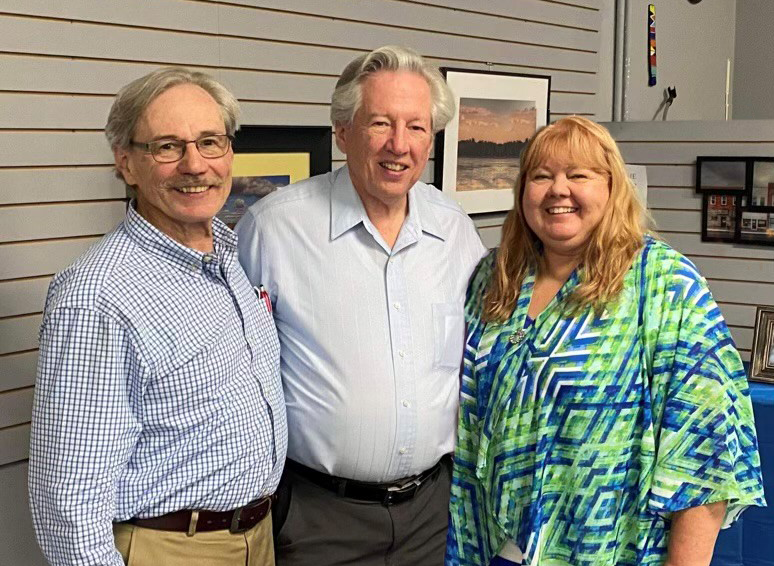 Two men and a woman smile for a photo.