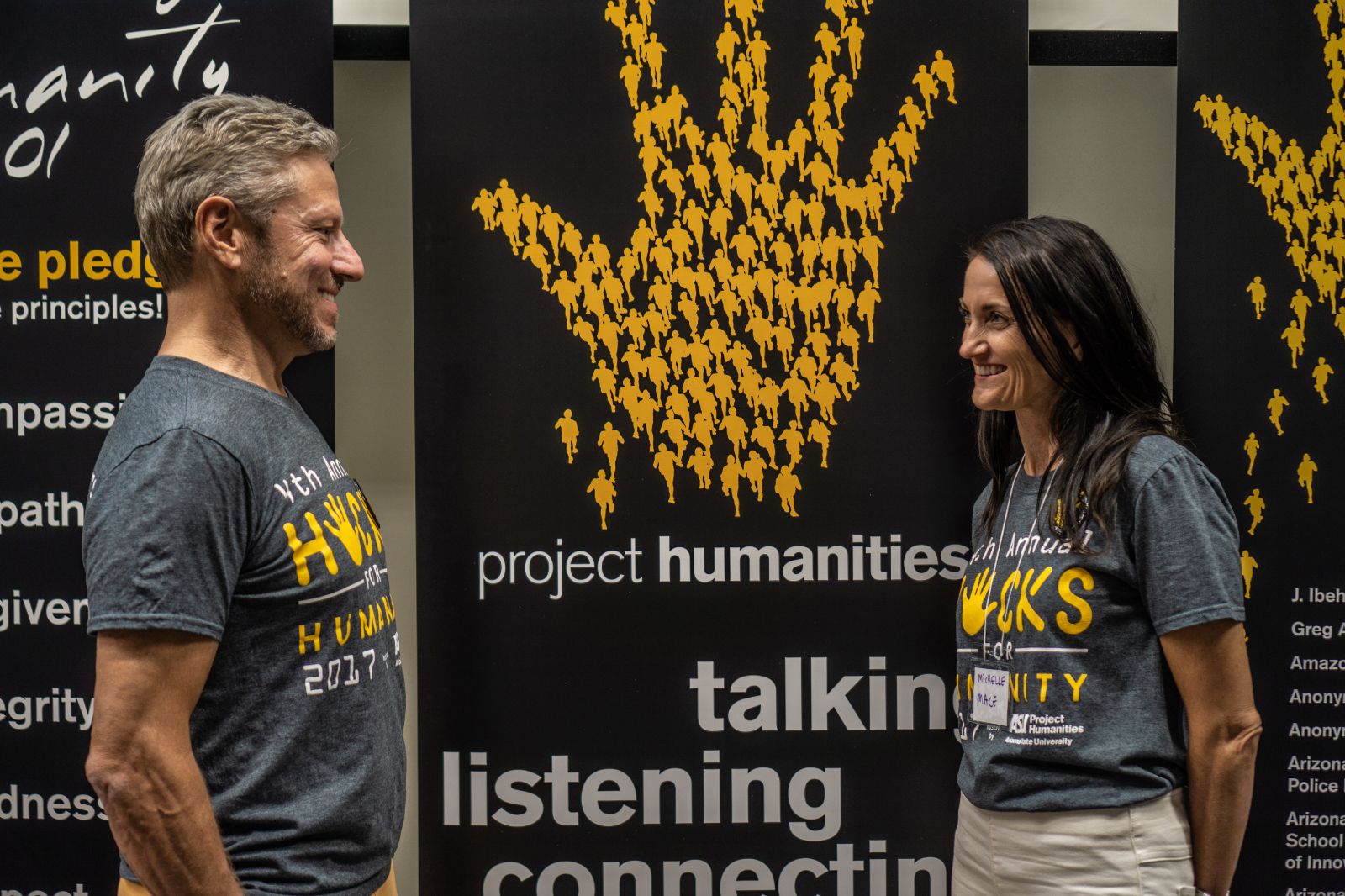 Male and female standing in front of a banner