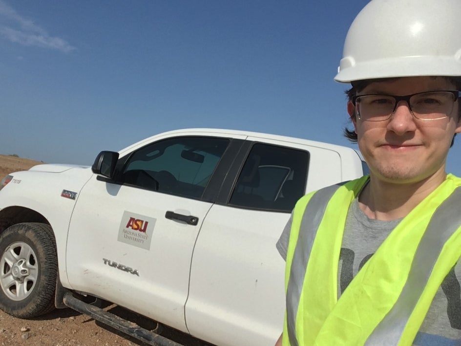  in a hard hat and yellow vest standing in front of a white ASU truck.