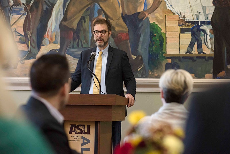 man speaking at lectern to a group