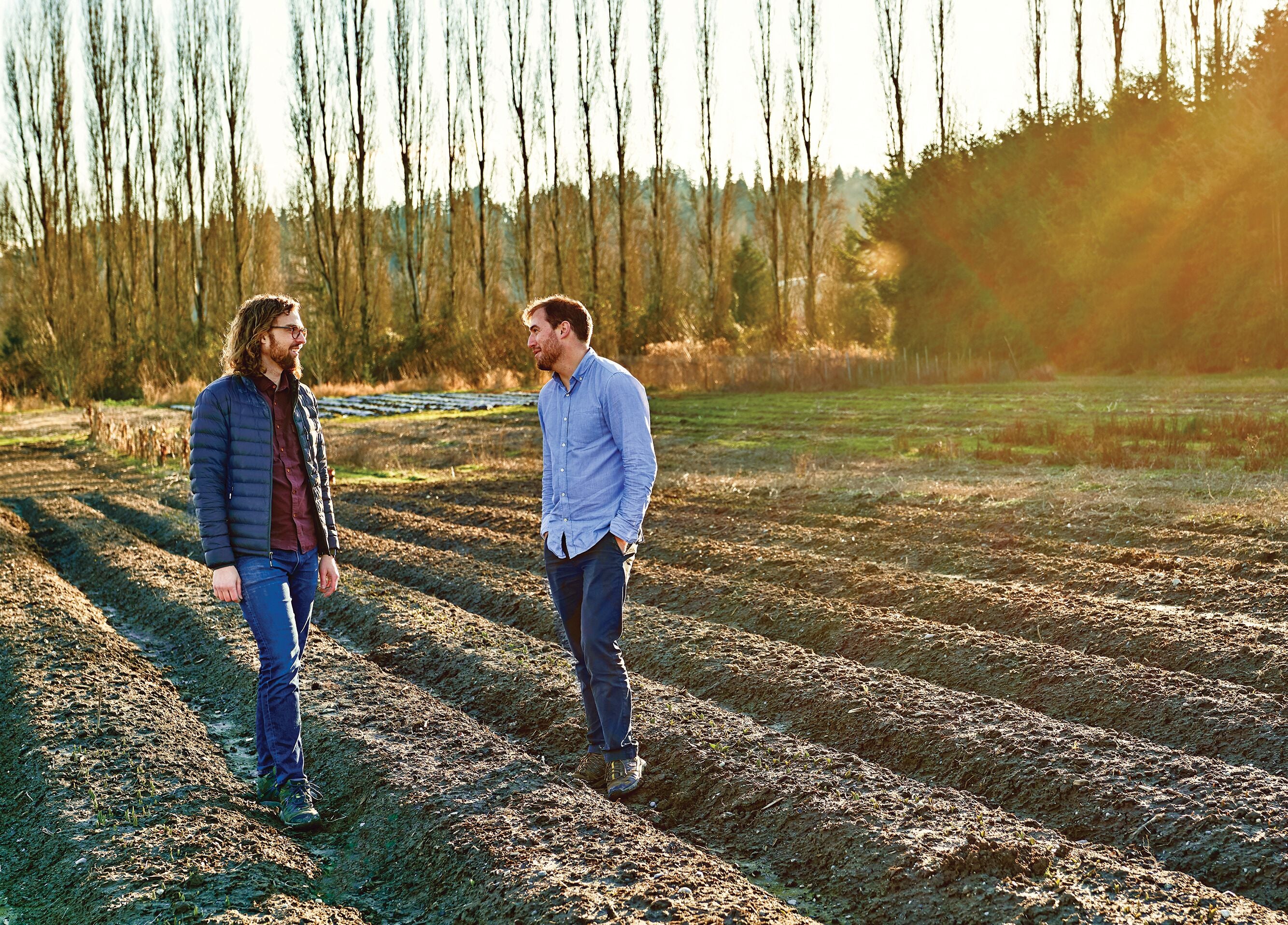 Two men stand in a farm field