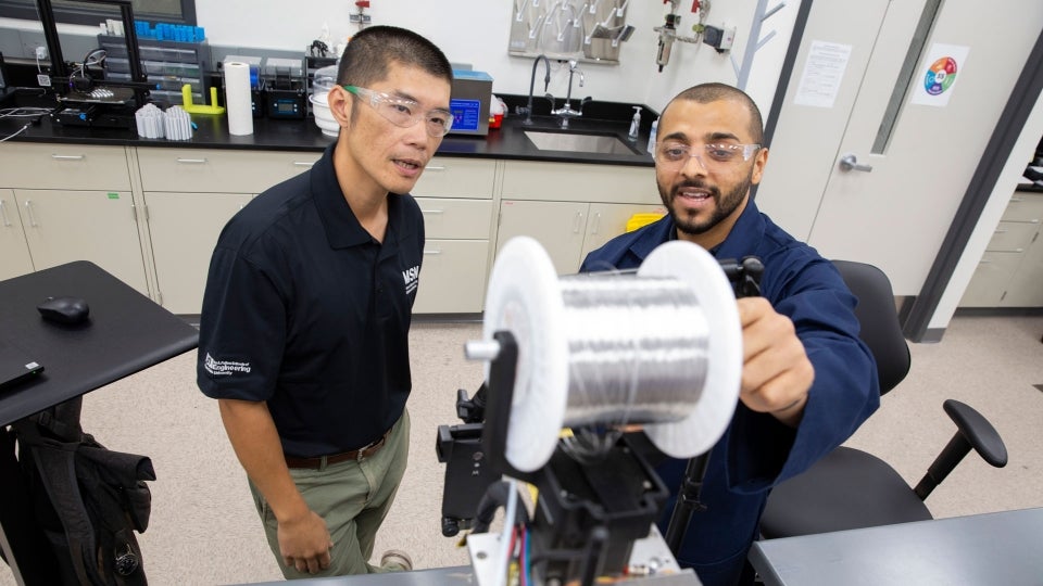 Two men in a lab using equipment.