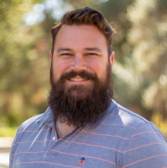 close-up of a smiling man with dark hari and a full beard