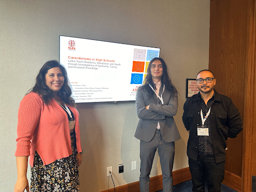 Three people standing next to a screen at a conference.