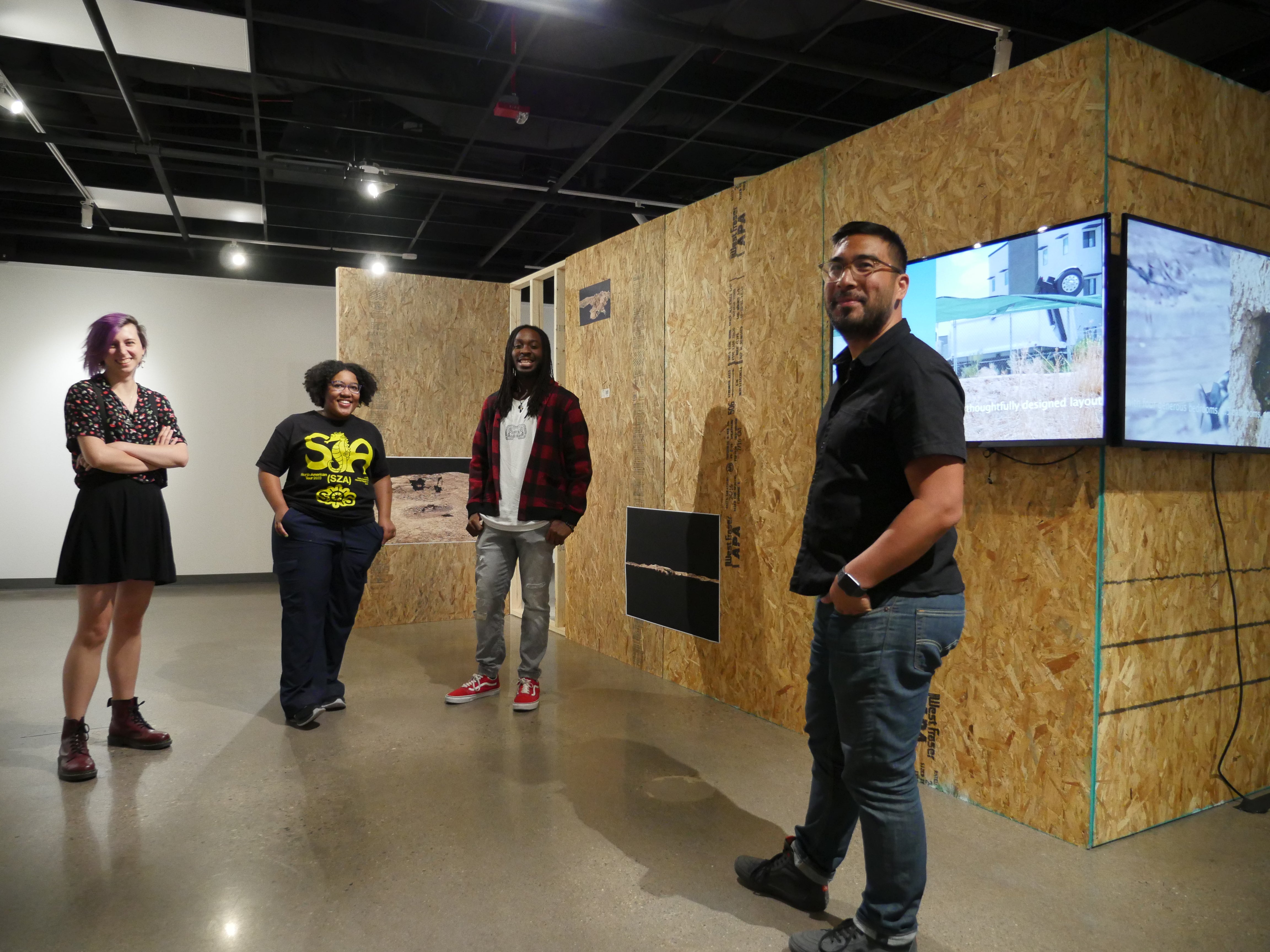 Group of four people posing for photo at exhibit opening