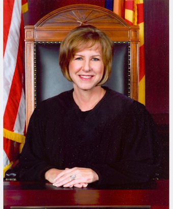 Woman in black robe sitting in wooden chair