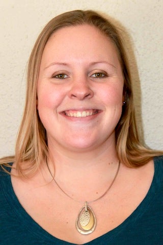 Woman with necklace and green shirt smiling