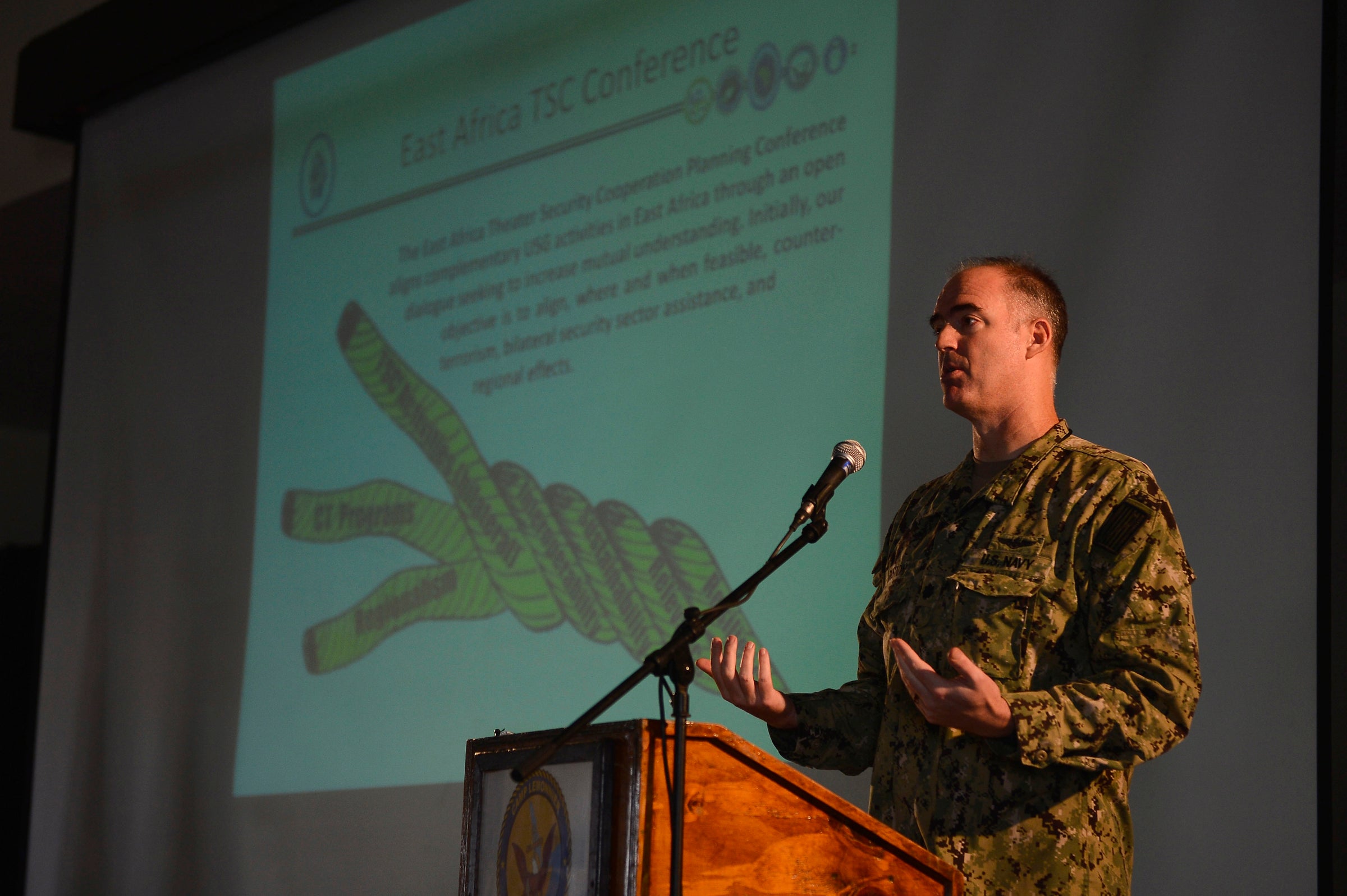 man in military fatigues speaking at podium