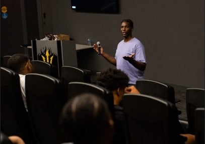 Man speaking to a crowd in a lecture hall.