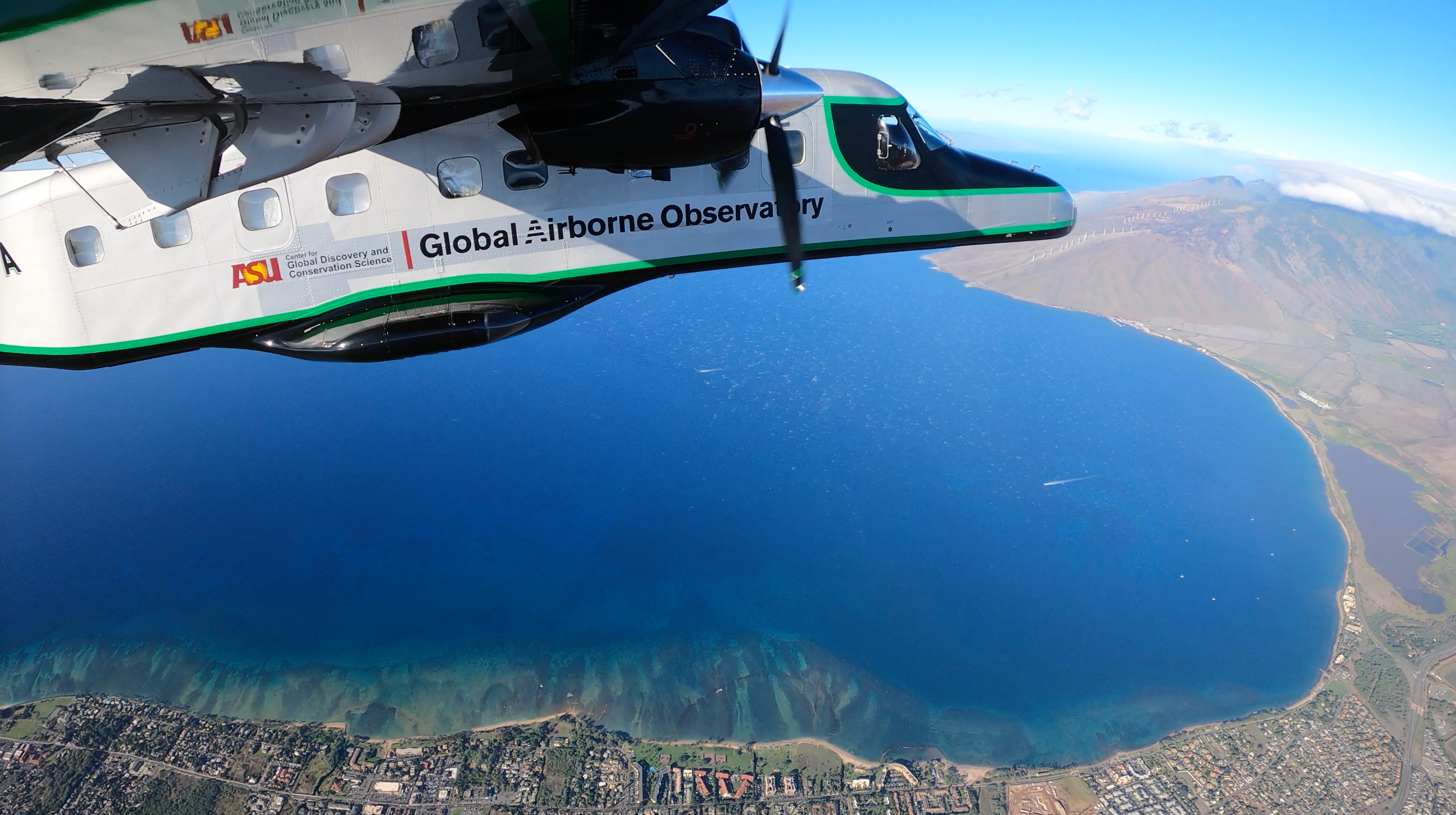 An airplane flies over the coral reefs of Hawaii