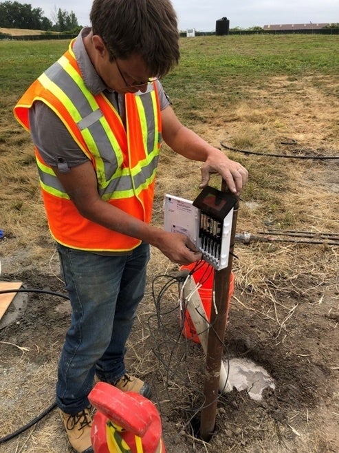 Leon van Paassen is pictured installing a solar-powered wireless data logger into the ground.