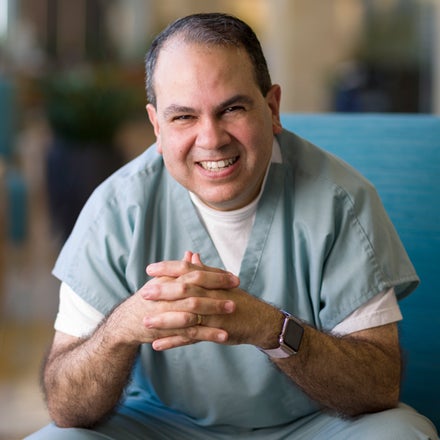 A man in medical scrubs sits in a chair