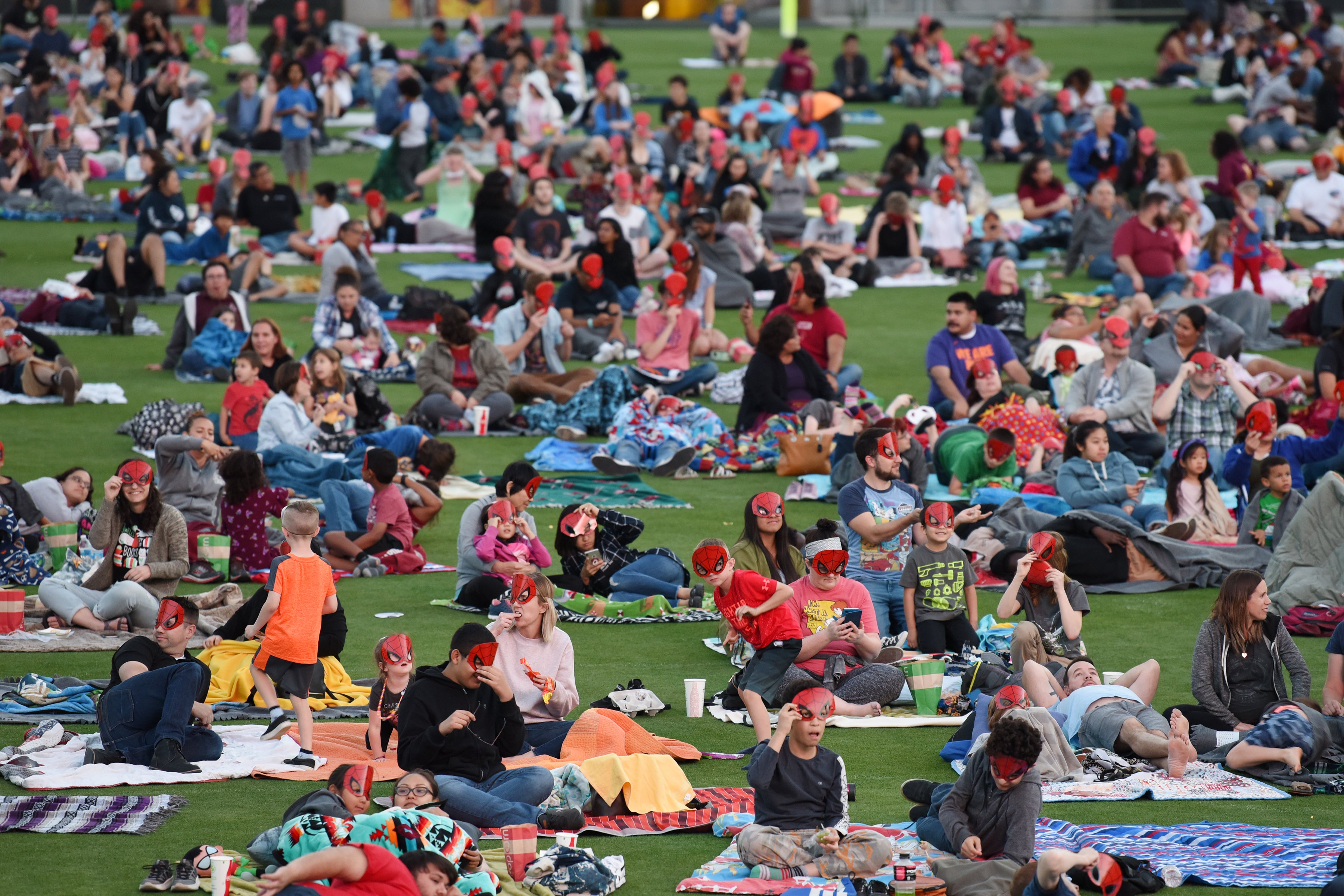 Family lie on blankets on the ASU football field to watch a Spider-Man movie