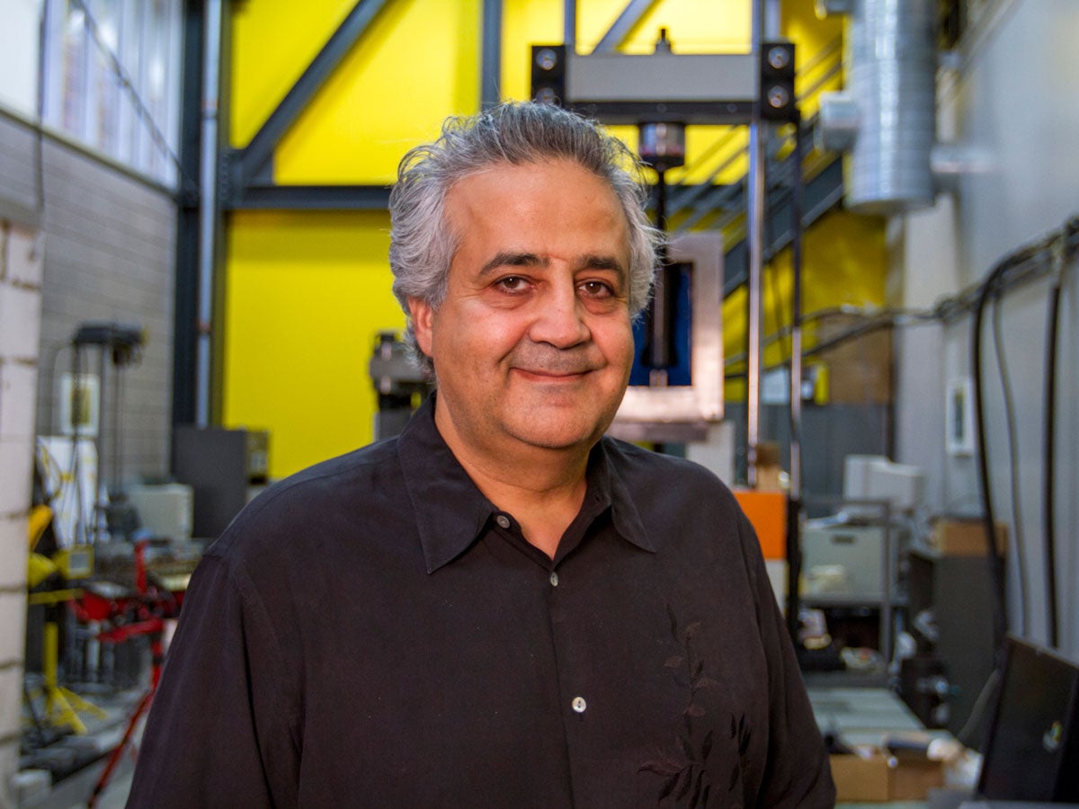 Barzin Mobasher stands in front of equipment in the Structural Mechanics and Infrastructure Materials Laboratory. 