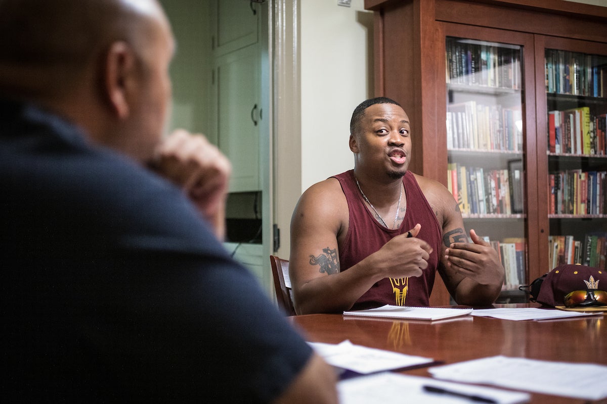 Man in tank top talking to another person