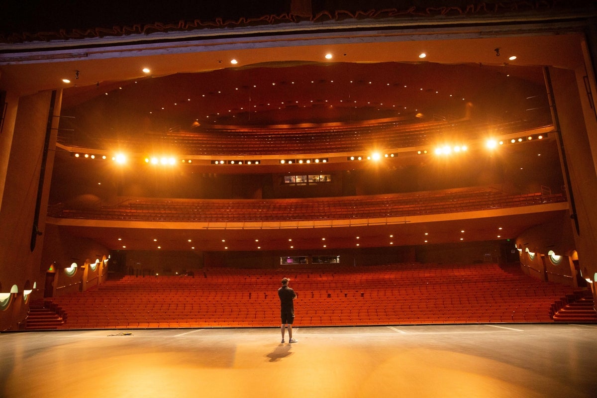 Man stands on a stage in an empty auditorium